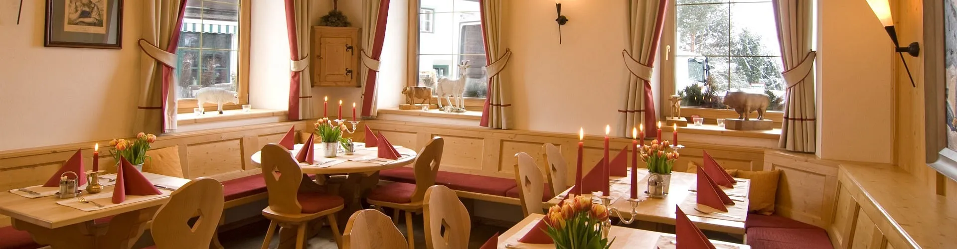 Ein Restaurant mit Holztischen und roten Stuhlgarnituren, Blumen auf den Tischen.